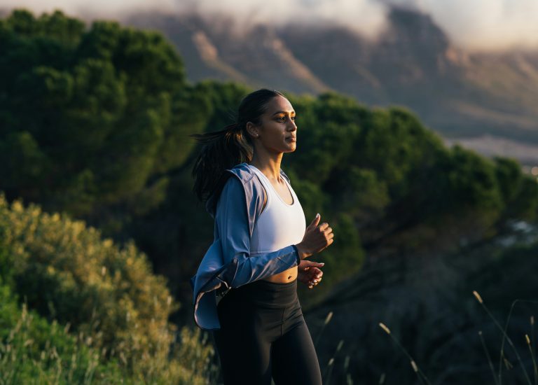 A woman enjoying a scenic outdoor jog, representing fitness and active living in harmony with nature.