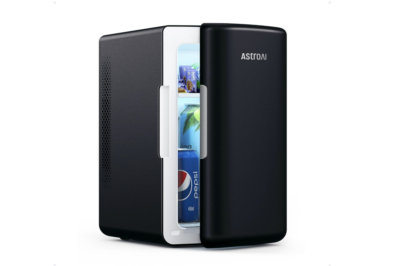 A sleek black AstroAI mini fridge with the door slightly open, revealing neatly stored beverages including a Pepsi can and other drinks.